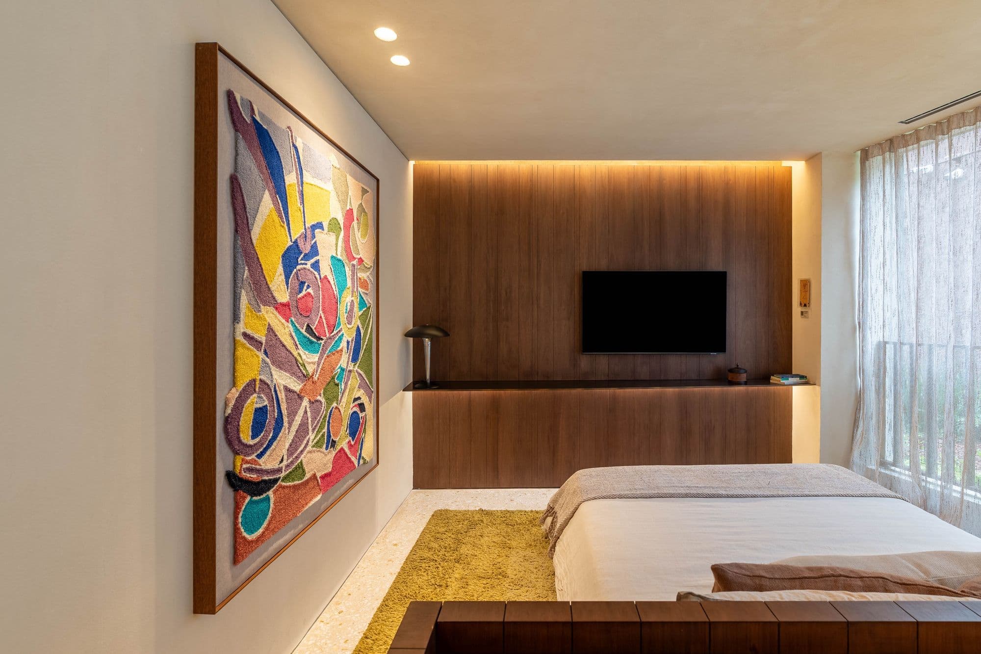 Quarto com painel de madeira iluminado e quadro colorido na parede lateral