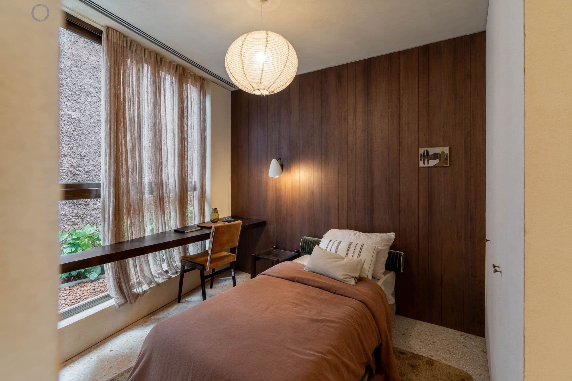 Quarto com parede de madeira, bancada de estudo e luminária pendente