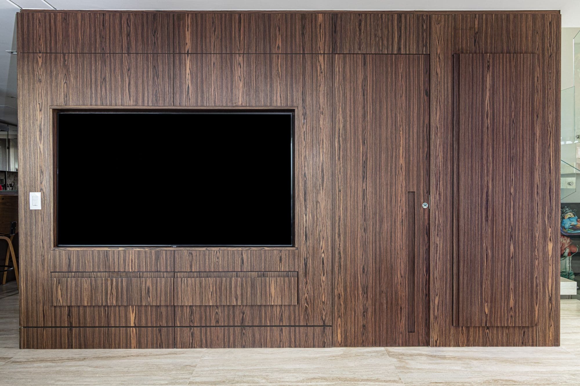 Painel de TV em madeira escura com portas embutidas sem puxador aparente