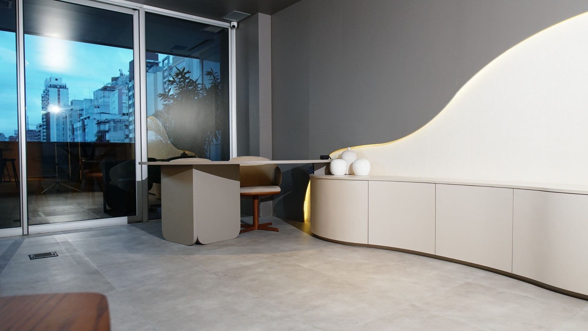 Showroom com móvel curvo branco iluminado e vista da cidade