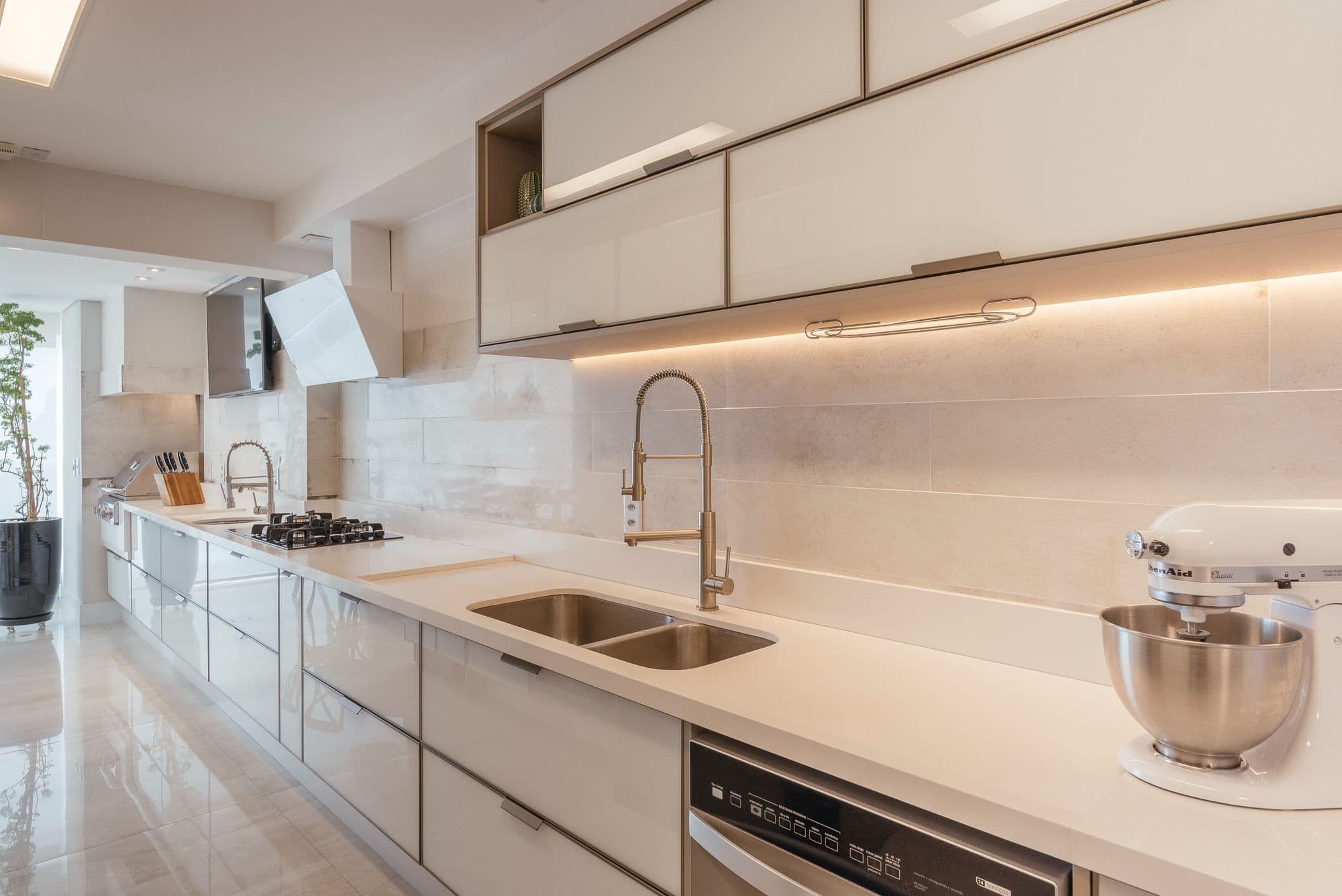 Cozinha com armários claros, cooktop e iluminação sob os armários