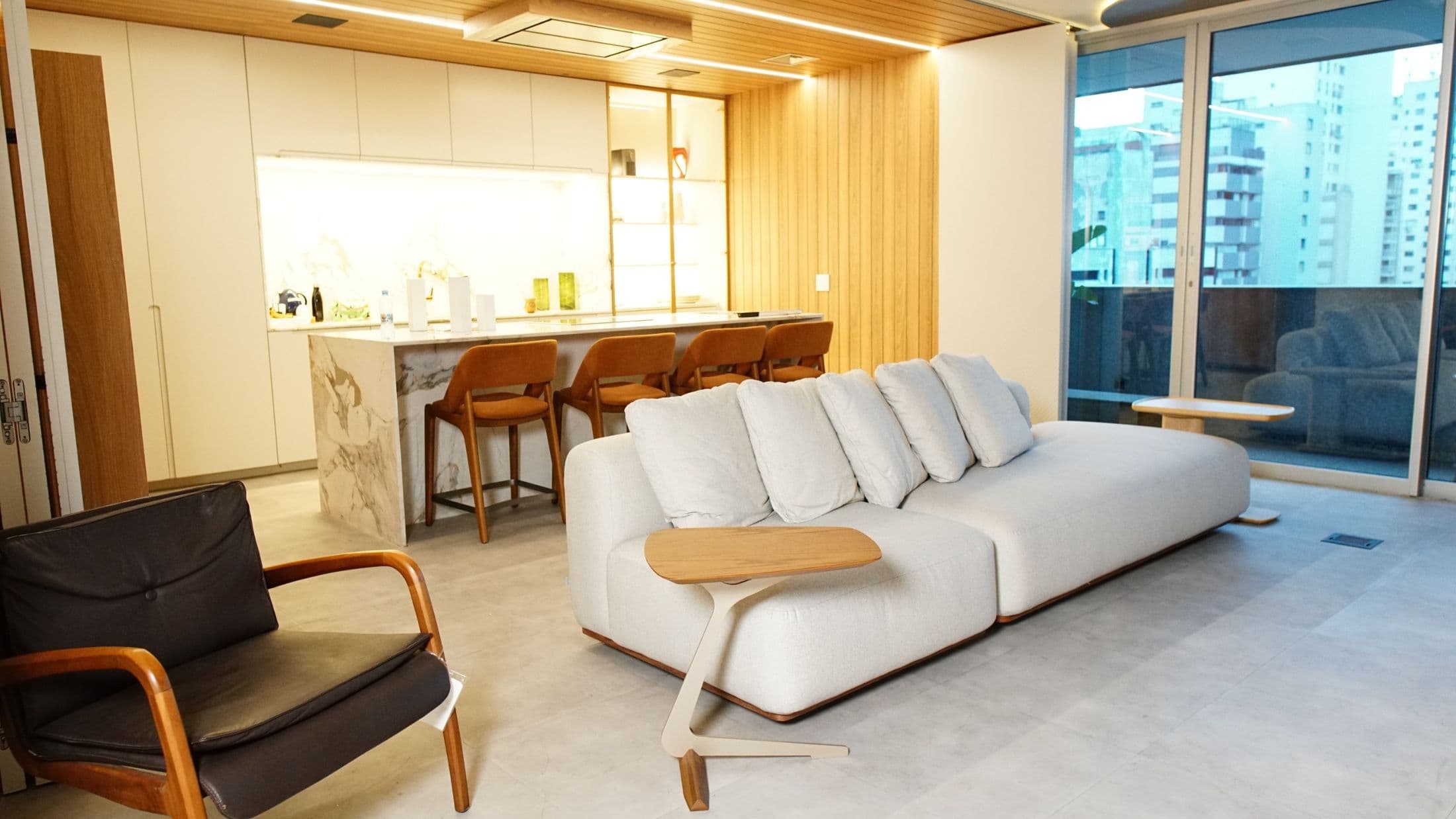 Estar do showroom com sofá branco e cozinha integrada ao fundo