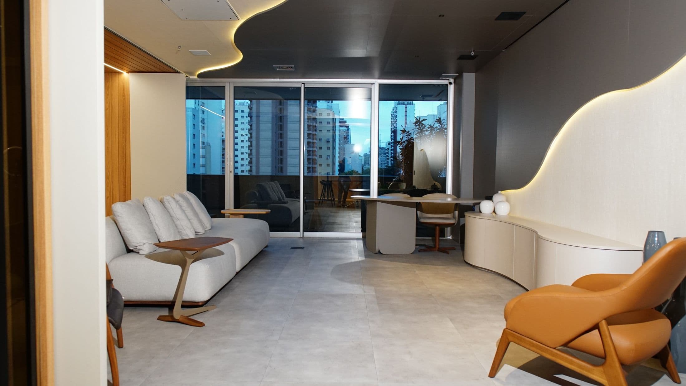 Estar do showroom com móvel curvo branco e vista da cidade
