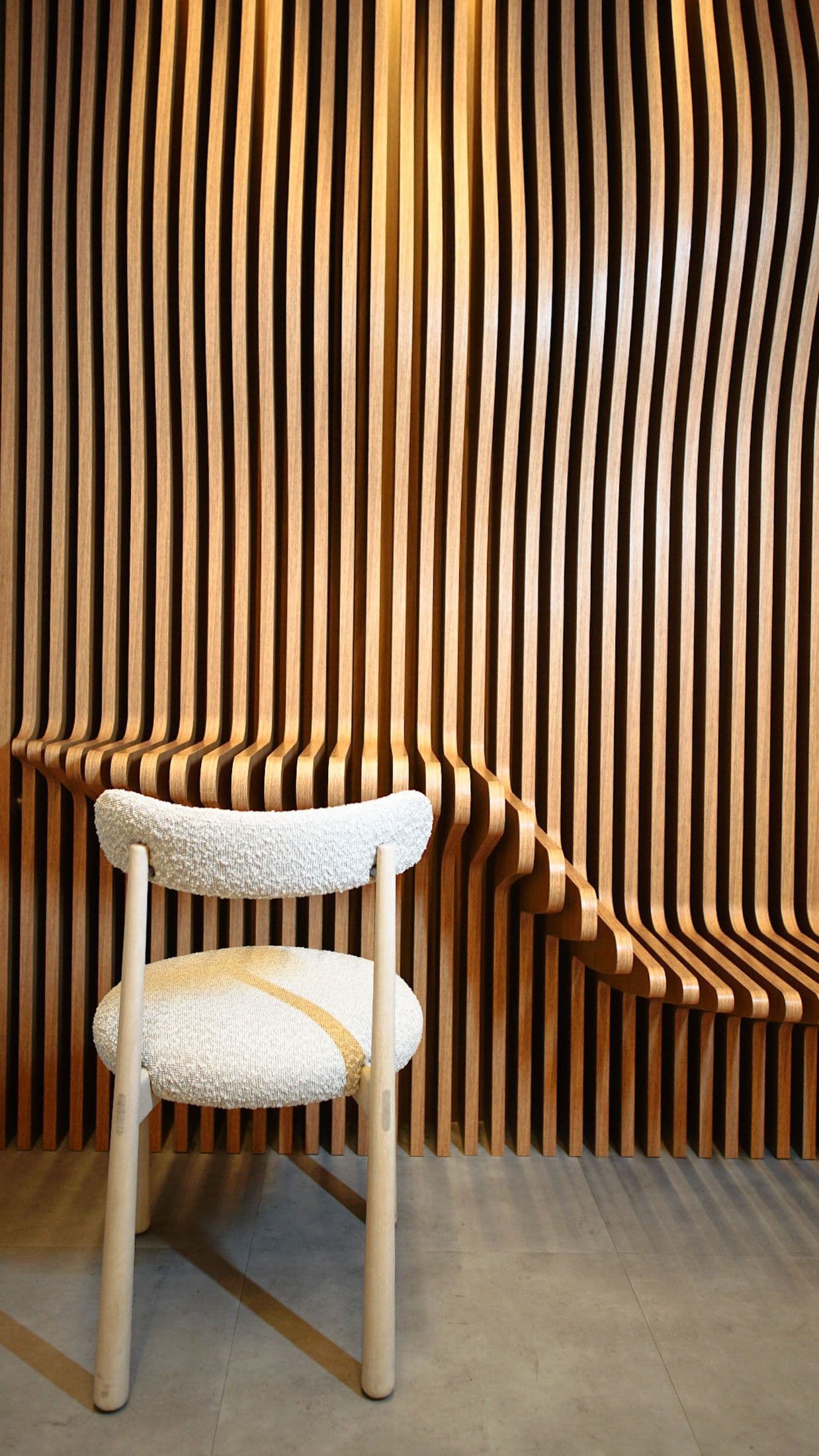 Ripas de madeira curvas formando um banco no showroom